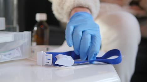 Close-up-of-medical-staff-picking-up-a-snap-tourniquet-band
